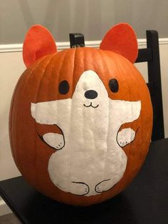 a pumpkin with a bear face painted on it's side and ears sticking out