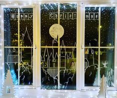 a window decorated with christmas lights and snowflakes in front of a night scene