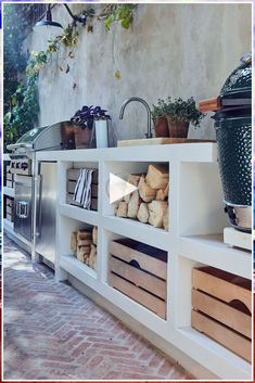 an outdoor kitchen with lots of wood stacked on top of it's shelfs