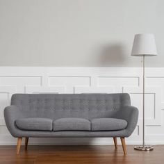 a grey couch sitting on top of a hard wood floor next to a white wall