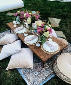 a table set with plates and flowers on a rug