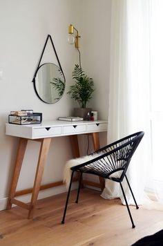 a white desk with a mirror, chair and potted plant