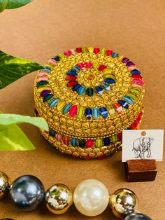 the beaded box is next to several beads and a card holder on a table