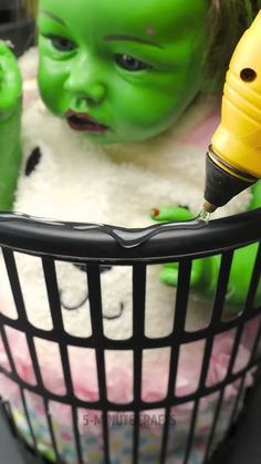 a baby with green hair in a basket next to another child's face and head