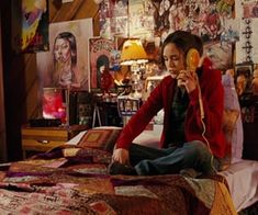 a woman sitting on top of a bed talking on a phone next to a quilt