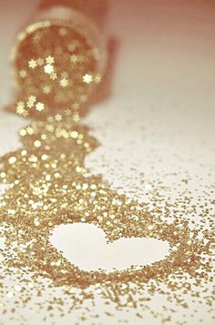 a gold glitter heart on a white surface