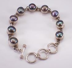 Vintage Unique Sterling Silver Black Pearl Bracelet. This bracelet is set with nine Black Pearls. These Pearls measure 7 mm in diameter each and are set in individual bezel settings. This bracelet weighs 20.1 grams, has a toggle clasp with adjustable loops and measures 7" in length. This bracelet will be shipped promptly in a gift pouch. Makes an awesome gift for any age, graduation, birthday or any special event. Black Pearl Bracelet, Black Pearls, Bracelet Black, Gift Pouch, Sterling Silver Bracelet, Toggle Clasp, Black Pearl, Tennis Bracelet, Chain Link Bracelet