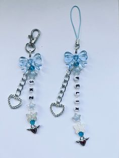 two key chains with charms attached to them on a white surface, one is blue and the other is silver