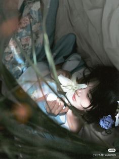 a woman laying on top of a bed next to flowers