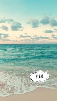 a person sitting on the beach with their feet in the water and there is a relax sign above them