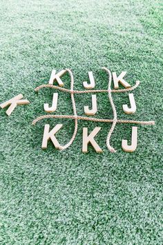 the letters are made out of wood and rope on the ground with green grass in the background