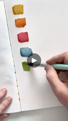 someone is drawing on paper with colored pencils and watercolor paints in front of them