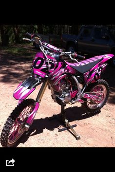 a pink dirt bike parked on top of a dirt field