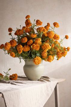 a white vase filled with orange flowers on top of a table