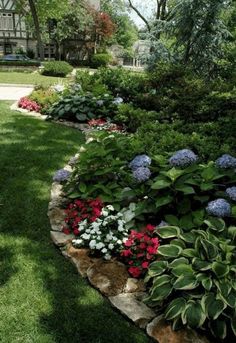 a garden filled with lots of flowers next to a lush green park covered in trees