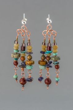 These long multi stone post chandelier earrings are a lavish pair of earthy earrings with jasper, turquoise, amazonite, magnesite, jade, and iolite natural stones, and glass and copper beads. Three beaded dangles swing on copper wire work bodies hung on sterling silver ball post earrings. The stones are all different shapes and textures in an earthy palette of gray, brown, red, and blue. These multi stone earrings with Bohemian style, are a bold and showy pair that will get you noticed. Wire Wrapped Copper Beaded Dangle Earrings, Bohemian Wire Wrapped Copper Earrings, Bohemian Brown Wire Wrapped Beaded Earrings, Copper Beaded Dangle Earrings With Dangling Beads, Bohemian Dangle Beaded Earrings With Natural Stones, Bohemian Beaded Dangle Earrings With Natural Stones, Bohemian Copper Earrings With Natural Stones, Bohemian Chandelier Dangle Earrings With Natural Stones, Bohemian Chandelier Earrings With Natural Stones