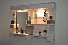 a mirror and shelf with jewelry on it in a room that has white painted walls