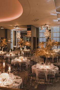 a room filled with lots of tables covered in white tablecloths and centerpieces