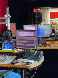 a man sitting at a desk in front of multiple computer monitors and sound mixing equipment