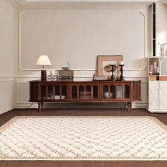 a living room with white walls and wood flooring on the side, along with a large area rug