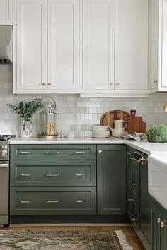 a kitchen with green cabinets and white counter tops, gold pulls on the cabinet doors