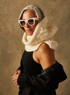 an older woman wearing white sunglasses and a scarf around her neck is posing for the camera