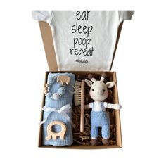 a toy giraffe and baby clothes in a box with the words eat sleep poop repeat