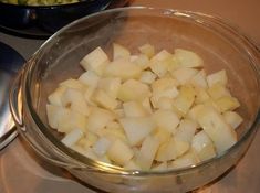 a bowl filled with chopped potatoes sitting on top of a stove next to another bowl