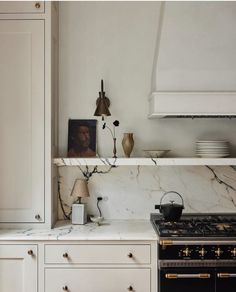 a kitchen with white cabinets and marble counter tops, gold trimming on the oven