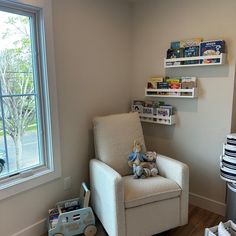 a baby's room with a rocking chair, bookshelf and stuffed animal