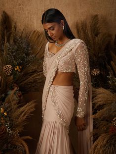 Dusty pink layered Saree with attached pre-draped and pre-stitched pallu featuring a hand embellished floral zardozi and mother of pearl border. Paired with a matching embellished blouse with a sweetheart neck & sheer sleeves, and a tie back.From Shloka Khialani 's Serendipity collection.DELIVERY TIMEPlease allow 6-8 weeks for your outfit to arrive.FABRIC DETAILSGeorgette, Net, CrepeProfessional cleaning only. Shloka Khialani, Pre Draped Saree, Indian Fits, Asian Couture, Pearl Border, Saree Gowns, Sarees Bridal, Drape Sarees, Trendy Outfits Indian