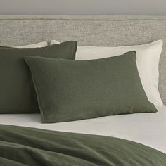 a bed with green pillows and white sheets