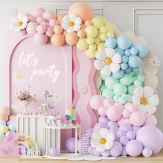 a party with balloons, flowers and other decorations on the wall in front of it