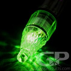 a green light is shining on the glass bottle with it's cap open and glowing in the dark