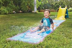 a young boy slides down a water slide in the yard