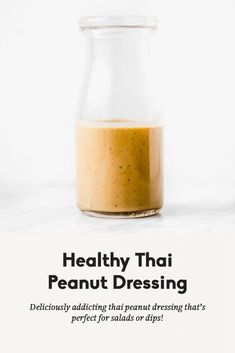 a glass jar filled with peanut dressing on top of a table