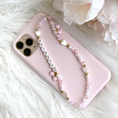 a pink phone case sitting on top of a white furnishing next to a flower