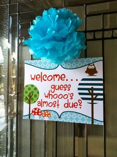 a welcome sign hanging from the side of a metal fence with a blue flower on top