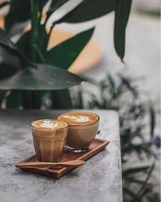 two cups of coffee sitting on top of a wooden tray