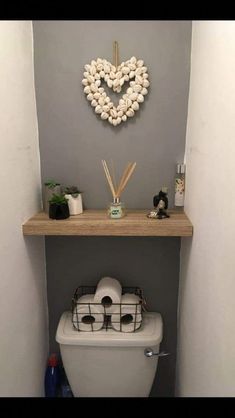 a white toilet sitting in a bathroom next to a wooden shelf with decorations on it