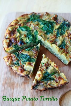 a pizza with spinach and cheese is cut into slices on a cutting board next to a knife