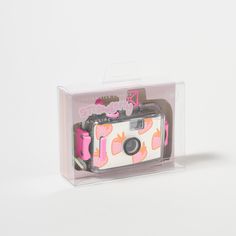 a camera in a clear box with pink and white designs on the front is shown