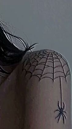 the back of a woman's head with a spider web tattoo on it