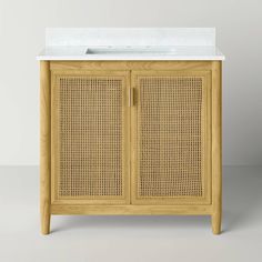 a bathroom vanity with a sink and wicker cabinet on the front, against a white wall