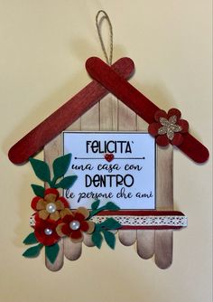 a sign hanging from the side of a wooden house with flowers and leaves on it