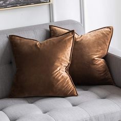 two brown pillows sitting on top of a gray couch