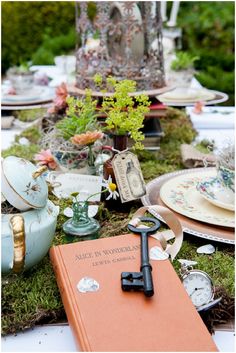 a table topped with lots of plates and a cross on top of moss covered ground