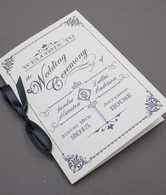 a wedding card with a black bow on it's side, sitting on top of a table