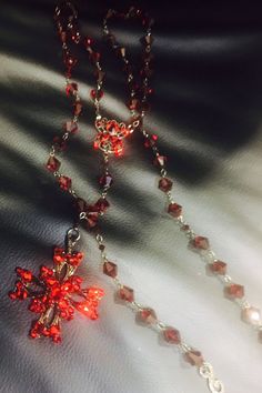 This is a beautiful red long necklace that can be adjusted and used multi ways. Wrap it around your neck for a choker look or adjust it to fit however you wish. Ruby red crystal beads plated in black . Cross has crystals on both sides. Handmade Red Cross Pendant Jewelry, Handmade Red Crucifix Jewelry, Spiritual Red Cross Pendant Necklace, Elegant Red Cross Pendant Jewelry, Red Adjustable Cross Necklace, Adjustable Red Cross Necklace, Rosary Style Necklace, Silver Mask, Silver Drop Necklace