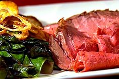 a close up of a plate of food with meat and spinach on the side